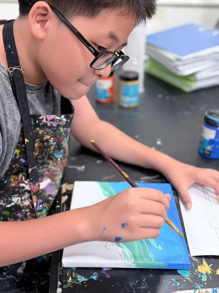 A student at 24Art is painting with watercolors